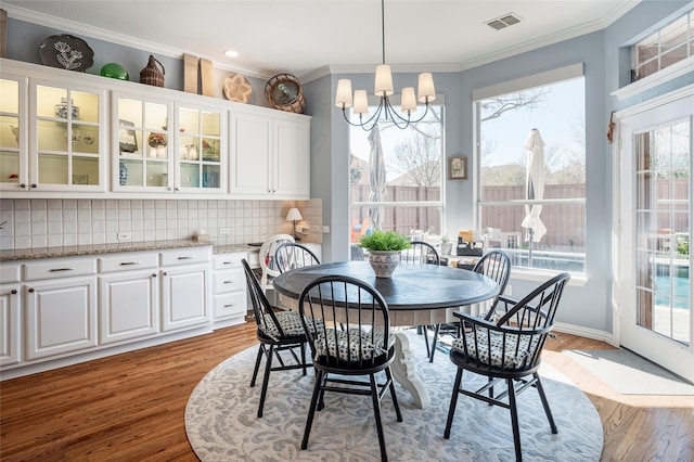 dining space featuring ornamental molding, a notable chandelier, and light hardwood / wood-style floors