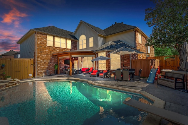 back house at dusk featuring outdoor lounge area, a fenced in pool, and a patio area