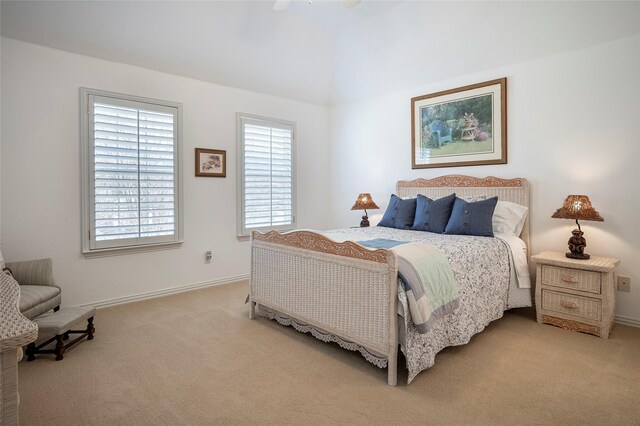 bedroom with ceiling fan, light colored carpet, and vaulted ceiling