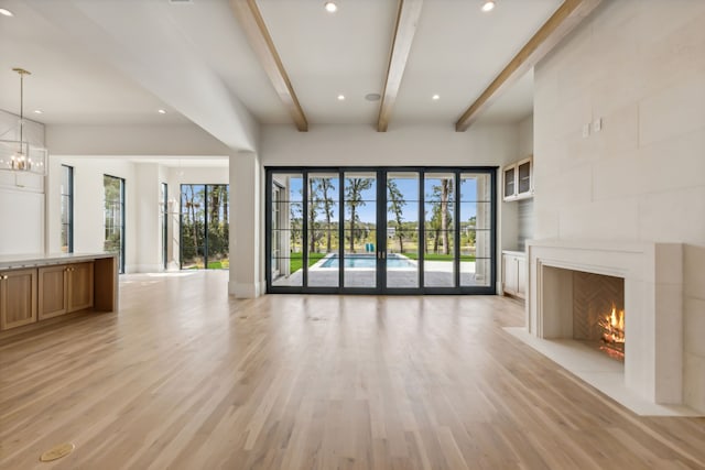 unfurnished living room featuring a healthy amount of sunlight, a high end fireplace, and light hardwood / wood-style flooring