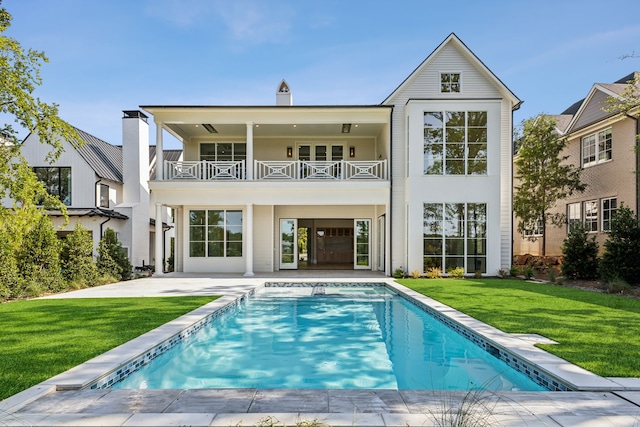 rear view of property featuring a patio, a balcony, and a yard