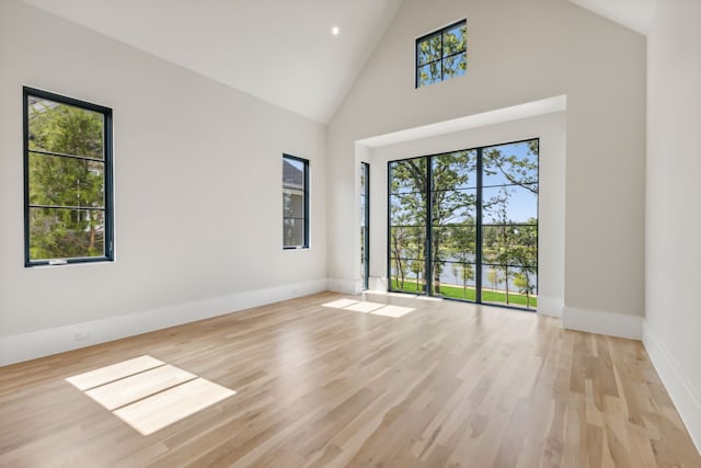 empty room with light hardwood / wood-style flooring and high vaulted ceiling