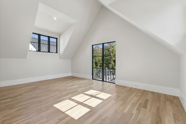 bonus room featuring high vaulted ceiling, a healthy amount of sunlight, and light wood-type flooring