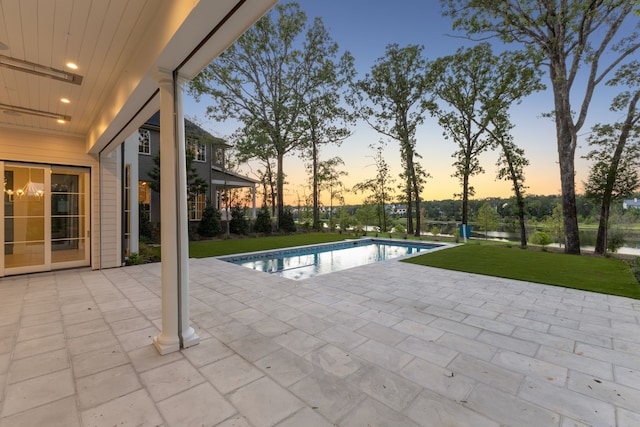 pool at dusk with a yard and a patio area