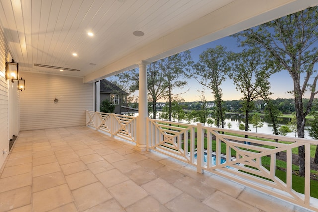 patio terrace at dusk featuring a water view