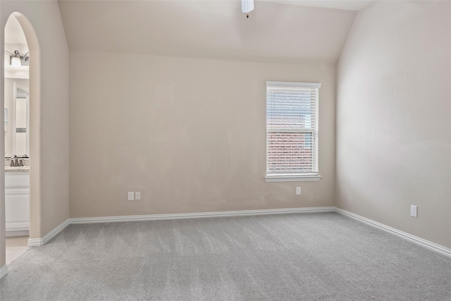 spare room featuring lofted ceiling, sink, and light carpet