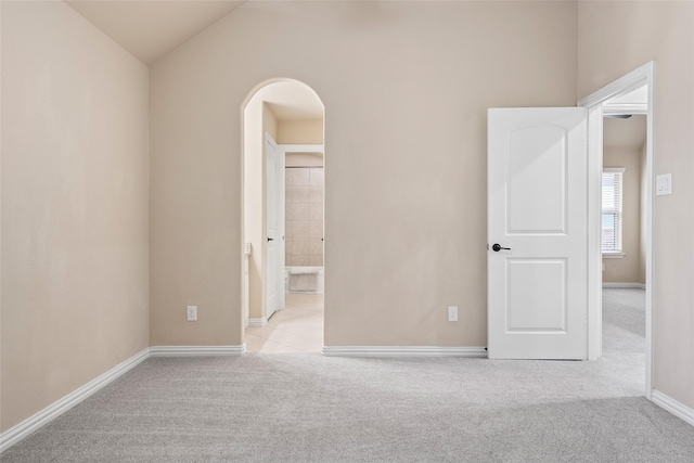 unfurnished bedroom featuring vaulted ceiling and light carpet