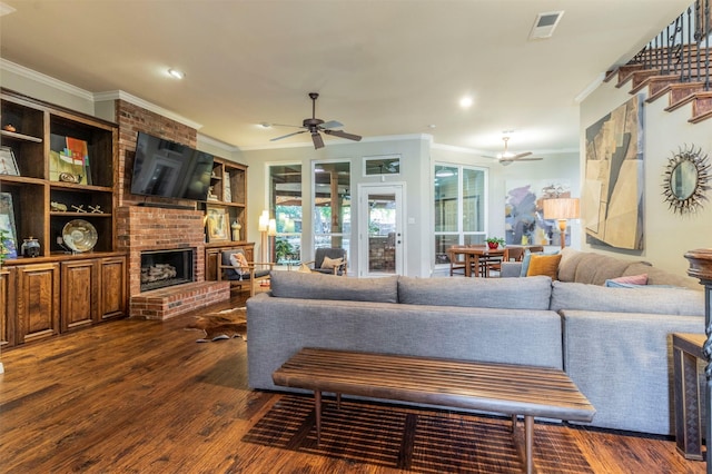 living room with crown molding, a brick fireplace, dark hardwood / wood-style floors, and ceiling fan