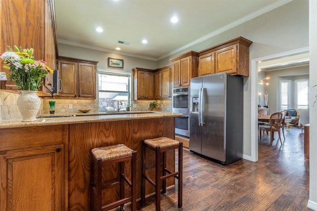 kitchen with stainless steel appliances, plenty of natural light, dark wood-type flooring, and a kitchen breakfast bar