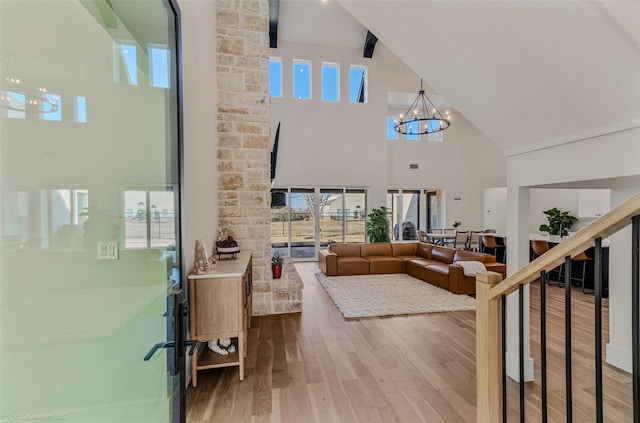 interior space featuring wood finished floors, a healthy amount of sunlight, a chandelier, beam ceiling, and high vaulted ceiling