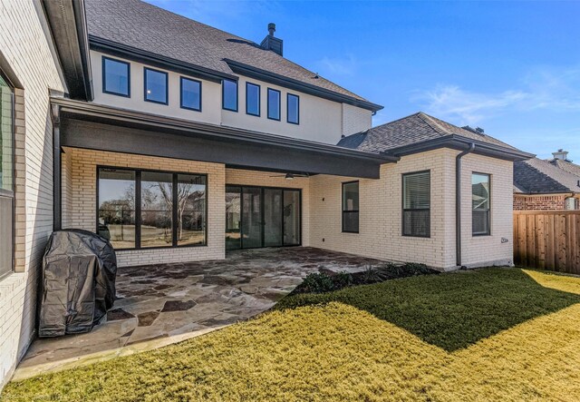 back of property with a patio, brick siding, fence, and a lawn