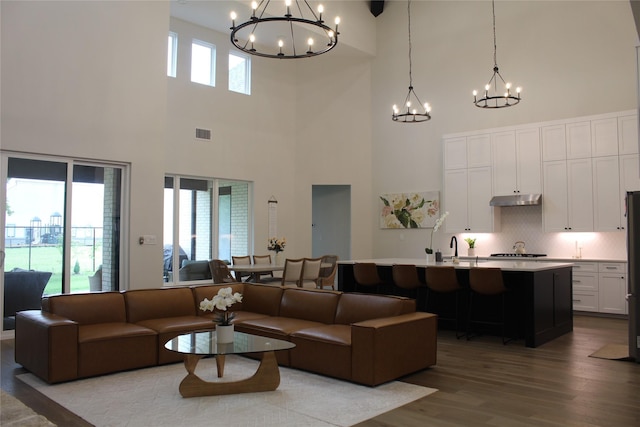 living room with a high ceiling, wood finished floors, and a chandelier