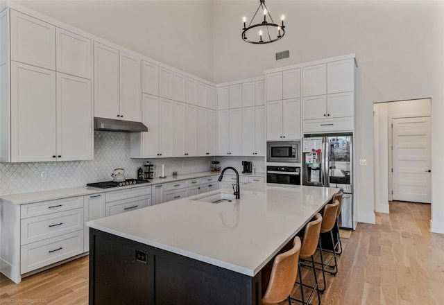7 Center Ct, Heath, TX 75032 - kitchen with a sink, appliances with stainless steel finishes, a towering ceiling, under cabinet range hood, and backsplash