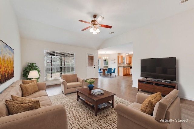 living room with lofted ceiling, sink, ceiling fan with notable chandelier, and light hardwood / wood-style flooring