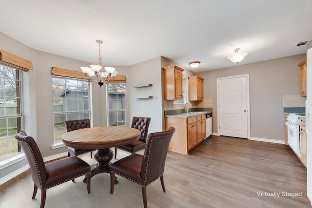 dining room featuring sink, hardwood / wood-style floors, and an inviting chandelier