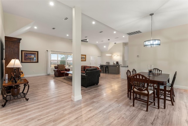 dining room with high vaulted ceiling and light hardwood / wood-style flooring