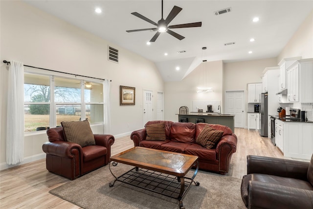 living room with ceiling fan, high vaulted ceiling, and light hardwood / wood-style floors