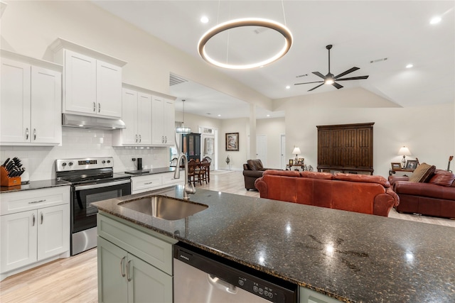 kitchen with sink, dark stone countertops, white cabinets, stainless steel appliances, and backsplash