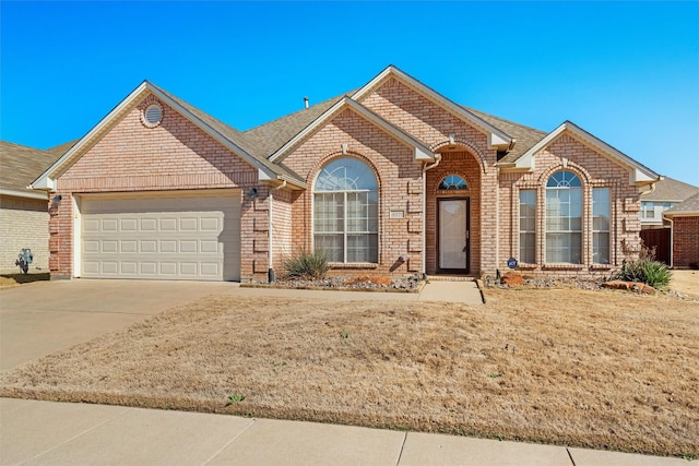 view of front of home featuring a garage, a front yard, concrete driveway, and brick siding