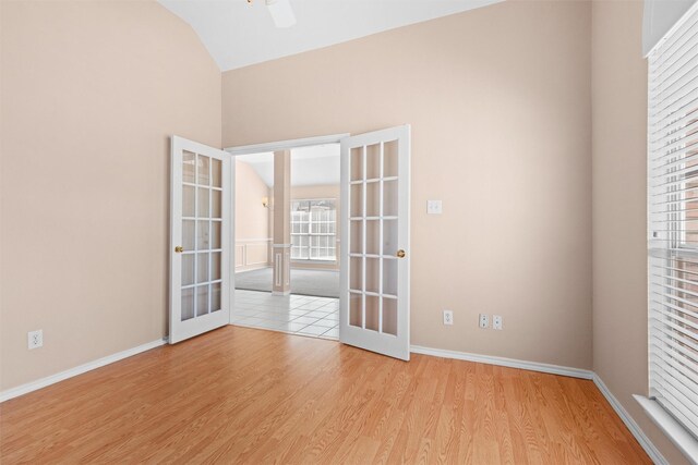 spare room with french doors, lofted ceiling, light wood-style floors, ceiling fan, and baseboards