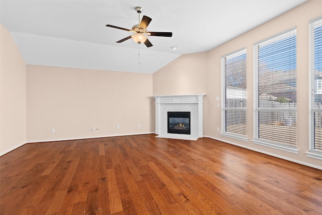 unfurnished living room featuring baseboards, a tile fireplace, ceiling fan, wood finished floors, and vaulted ceiling