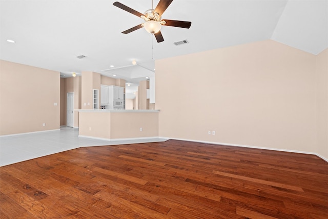 unfurnished living room featuring wood finished floors, visible vents, baseboards, vaulted ceiling, and a ceiling fan