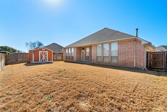 rear view of house featuring a fenced backyard, brick siding, a shingled roof, an outdoor structure, and a shed