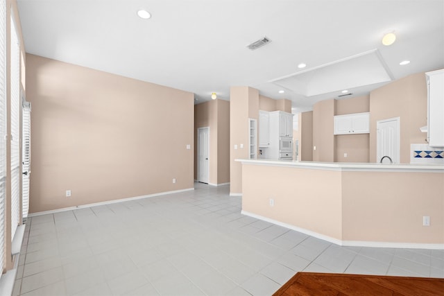 kitchen with recessed lighting, light countertops, visible vents, white microwave, and white cabinets