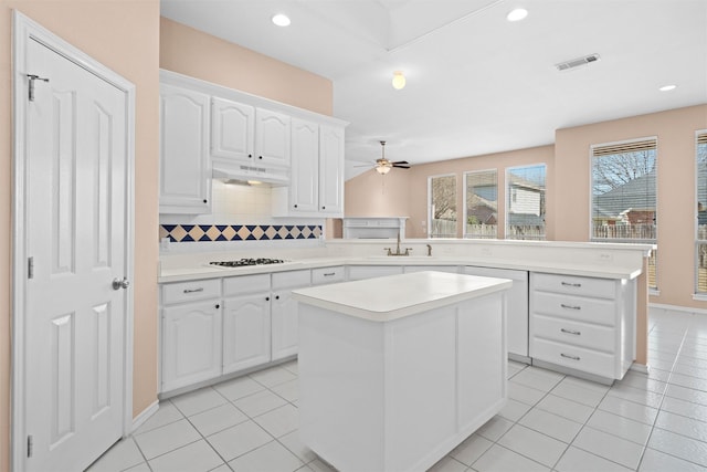 kitchen with light countertops, a kitchen island, white cabinetry, and under cabinet range hood