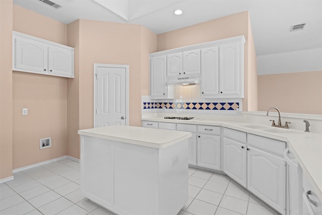 kitchen with light countertops, white cabinets, a sink, and under cabinet range hood