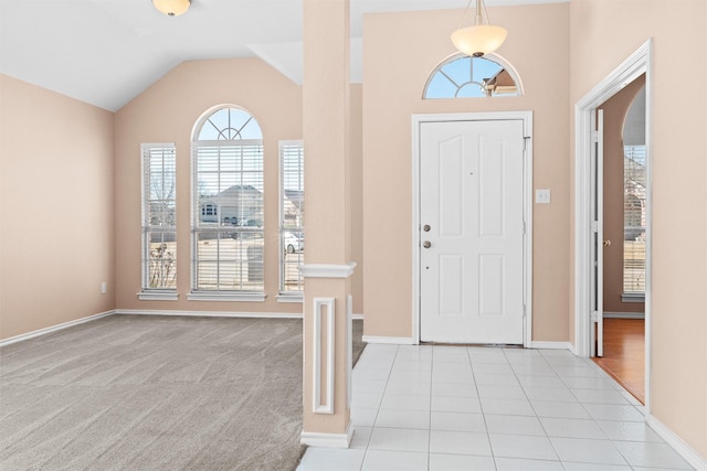 foyer with light tile patterned floors, baseboards, vaulted ceiling, and light colored carpet