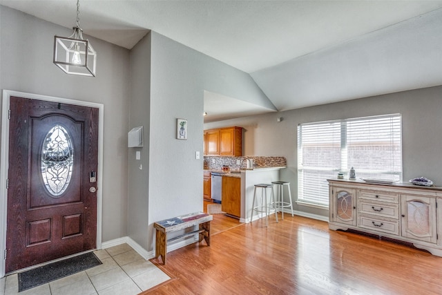 foyer entrance with vaulted ceiling and light wood-type flooring