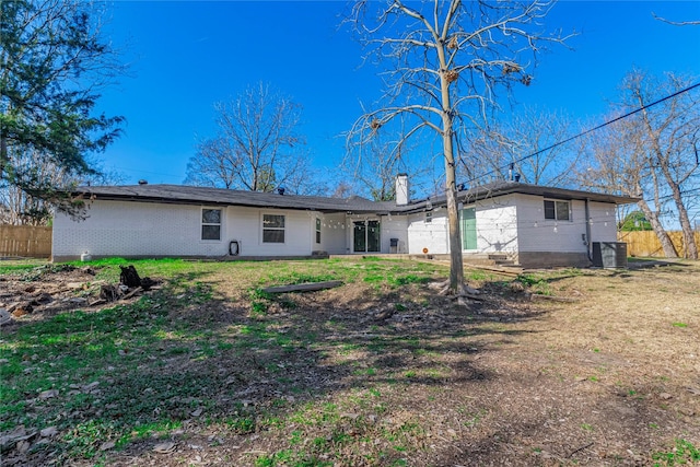 back of property with central AC and a lawn