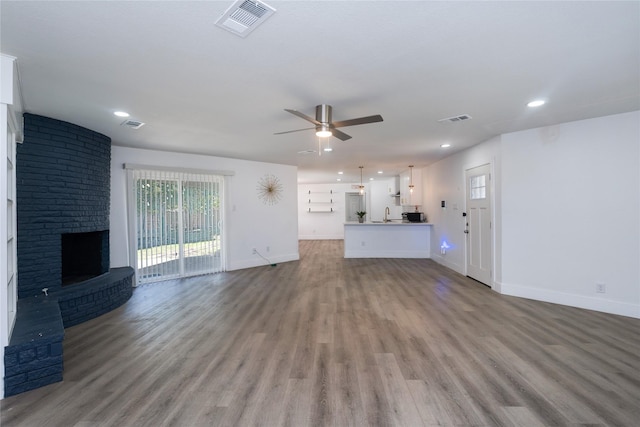 unfurnished living room with ceiling fan, a brick fireplace, and light hardwood / wood-style floors