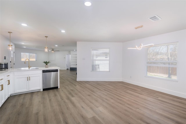 kitchen with sink, hanging light fixtures, light wood-type flooring, appliances with stainless steel finishes, and white cabinets