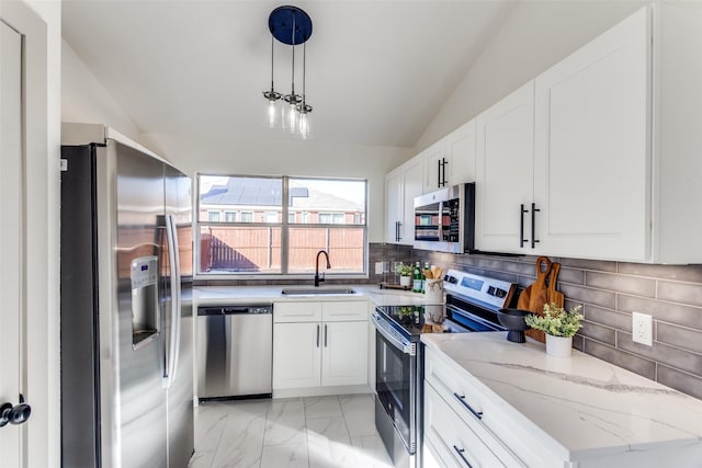 kitchen featuring sink, white cabinetry, vaulted ceiling, appliances with stainless steel finishes, and pendant lighting