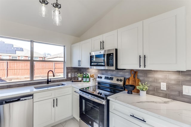 kitchen featuring lofted ceiling, sink, appliances with stainless steel finishes, white cabinets, and backsplash