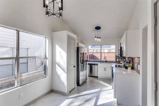 kitchen featuring pendant lighting, sink, stainless steel appliances, tasteful backsplash, and white cabinets