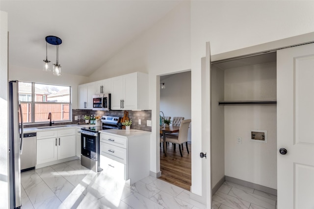 kitchen with pendant lighting, sink, appliances with stainless steel finishes, white cabinetry, and tasteful backsplash