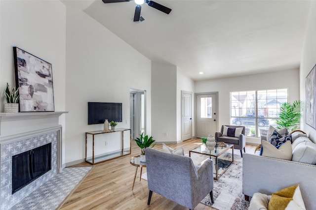 living room featuring light hardwood / wood-style flooring, a premium fireplace, and ceiling fan