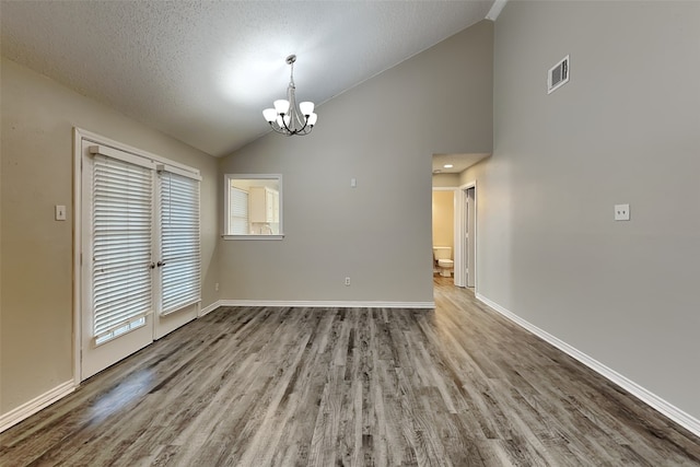 unfurnished dining area featuring a notable chandelier, light hardwood / wood-style flooring, high vaulted ceiling, and a textured ceiling