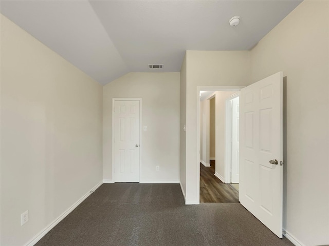 unfurnished bedroom featuring dark carpet and vaulted ceiling