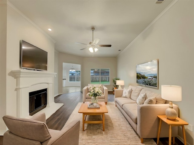 living room with crown molding, wood-type flooring, and ceiling fan