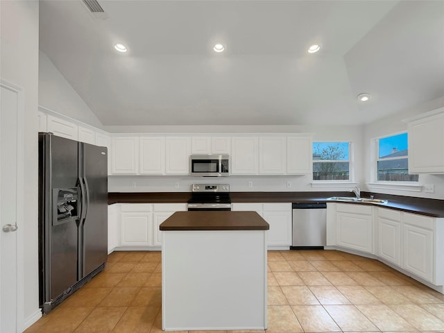 kitchen with light tile patterned flooring, appliances with stainless steel finishes, sink, white cabinets, and a center island