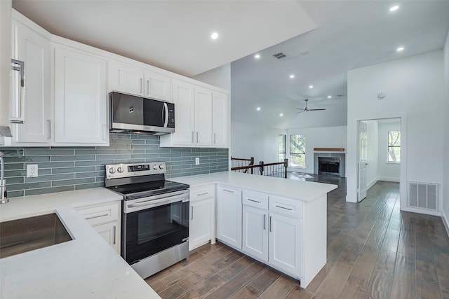 kitchen featuring sink, white cabinets, kitchen peninsula, stainless steel appliances, and dark wood-type flooring