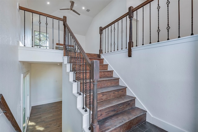 stairs with wood-type flooring, a towering ceiling, and ceiling fan