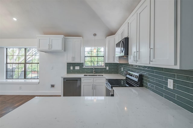 kitchen with sink, white cabinetry, light stone counters, pendant lighting, and stainless steel appliances