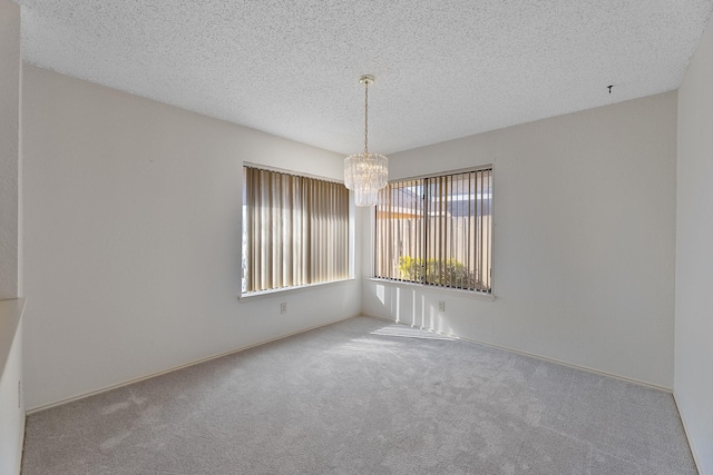 empty room with an inviting chandelier, carpet floors, and a textured ceiling