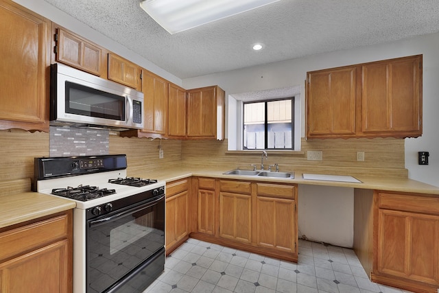 kitchen with gas range, sink, backsplash, and a textured ceiling