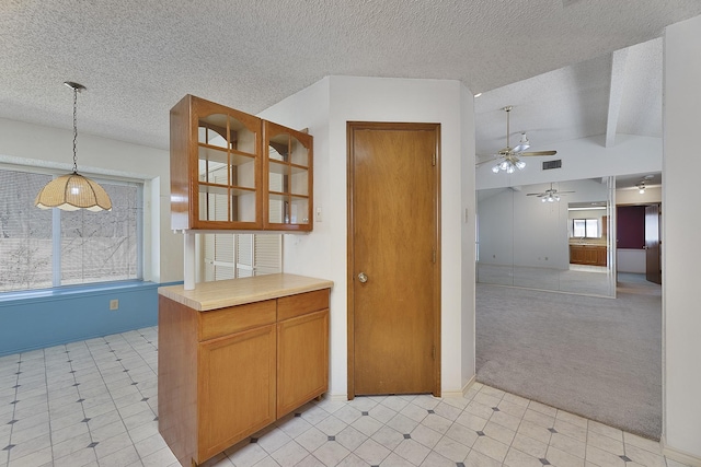 kitchen featuring lofted ceiling, decorative light fixtures, light colored carpet, a textured ceiling, and ceiling fan